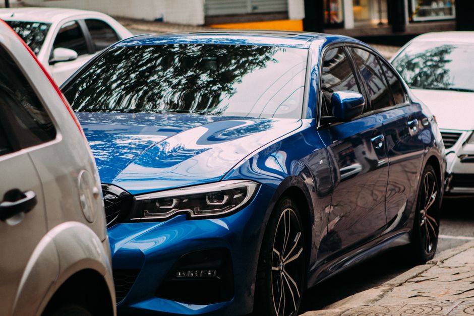 A vibrant blue luxury sedan parked on an urban street
