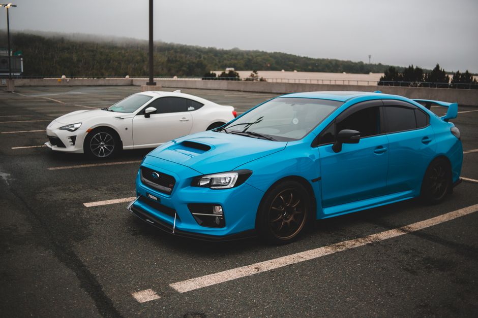 Modern fast clean automobiles parked on concrete surface with stripes on gloomy cloudy day
