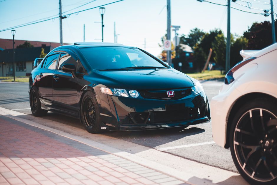 Black vehicle parked on asphalt road in city street sunlight
