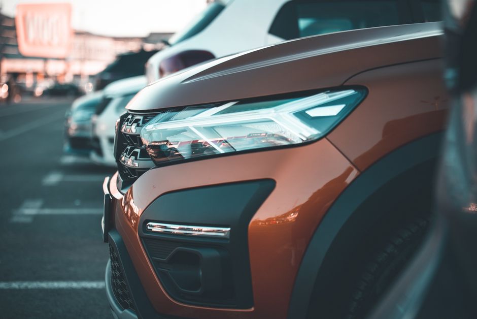 Close-up of a modern car's headlight in a parking lot at dusk